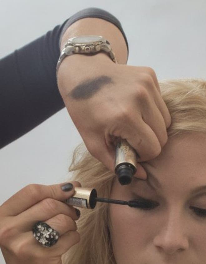 Zwei Hände führen Mascara und Lidstift am Auge einer Kundin